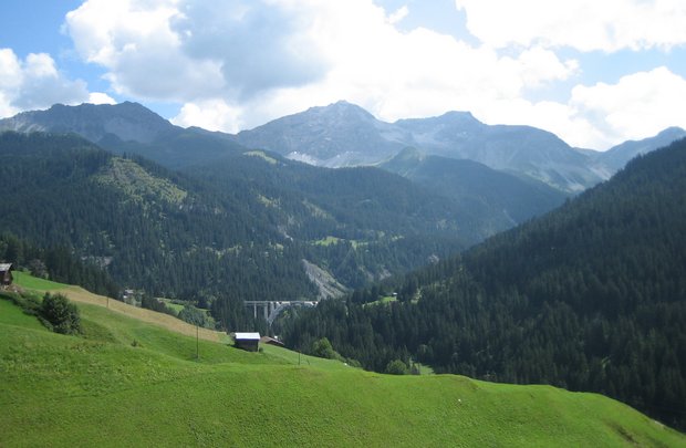 Foto mit Blick über ein Tal, in der Ferne ein Viadukt (Eisenbahnbrücke).