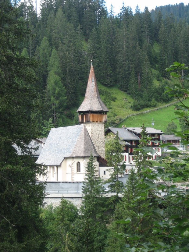 Foto eines Bergdorfs mit einer Kirche und einem Haus dahinter